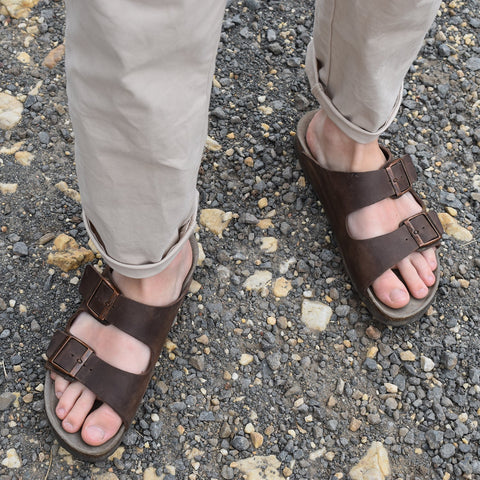 Man wearing brown leather sandal with double foot strap