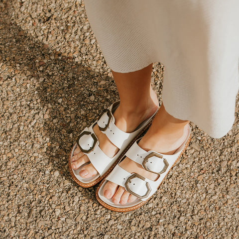 Woman wearing white leather sandals with two foot straps and chunky sole